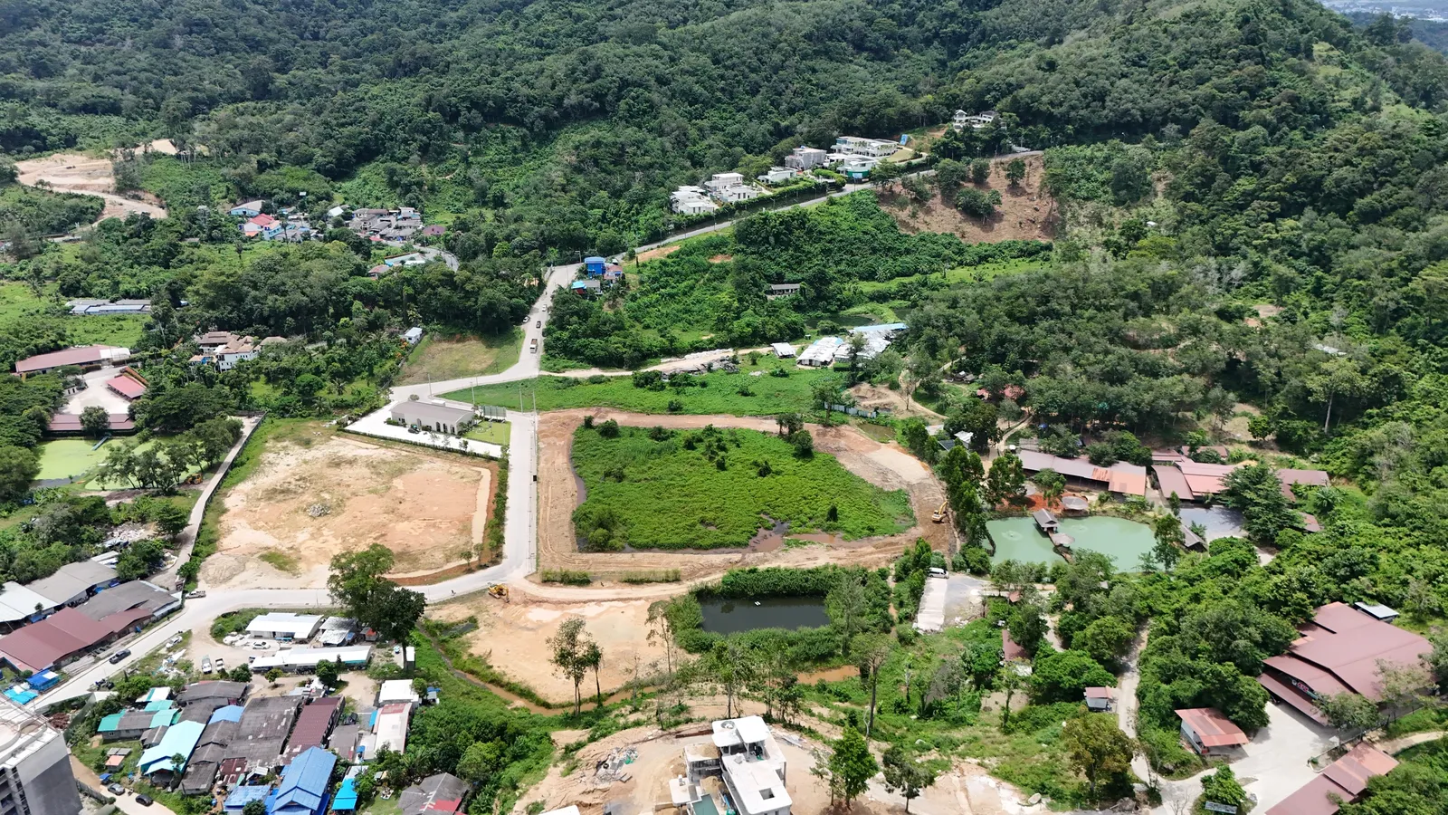 Aerial photo of the Sea Heaven estate: internal roads and cleared plots among forested hills